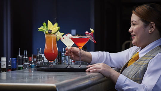 Cocktails being placed on a tray by staff in the North Cape Bar on Spirit of Adventure
